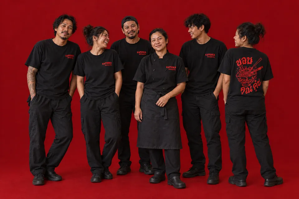 Équipe fictive de restaurant thaï avec une cheffe, en tenues noires Kapunka sur fond rouge